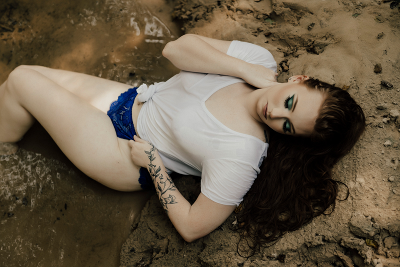 Boudoir Photographer, woman lays in sand in t-shirt and shirts